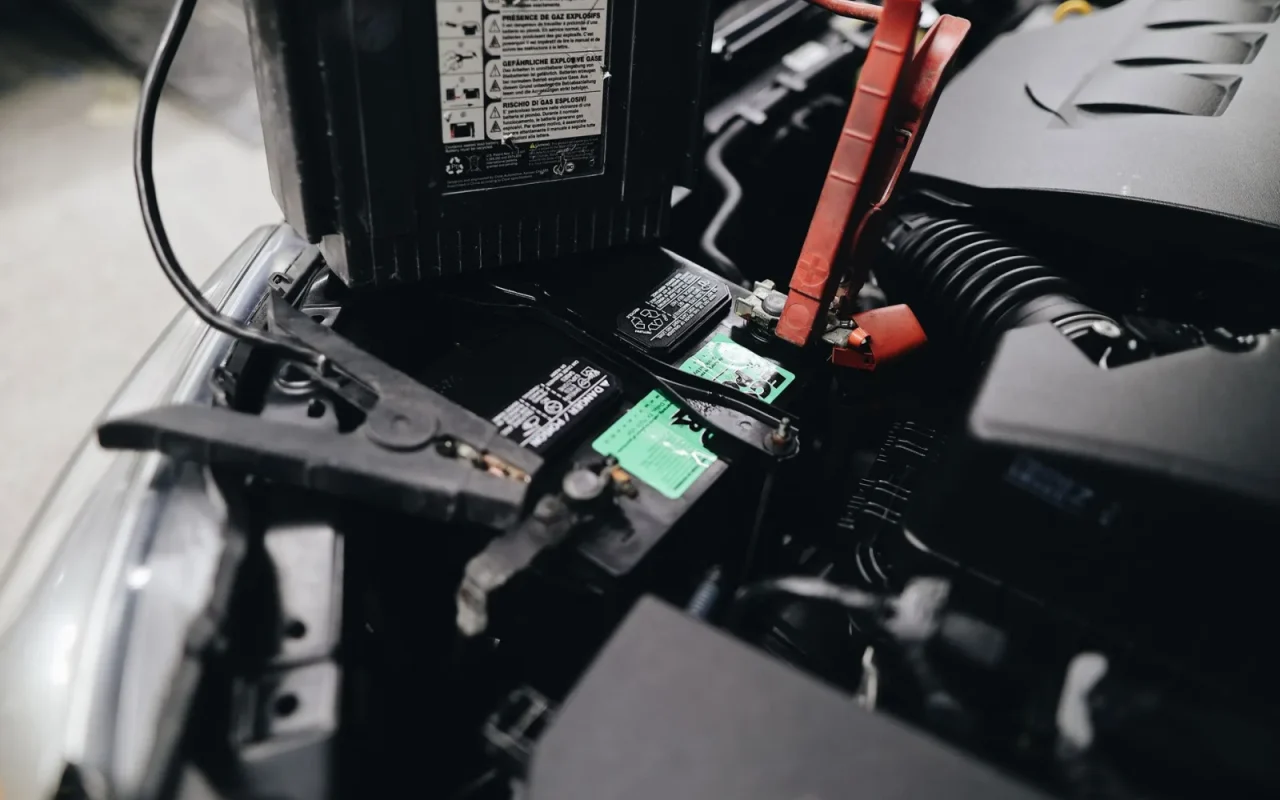 Robot mower docked on its charging base in shade with battery indicator visible
