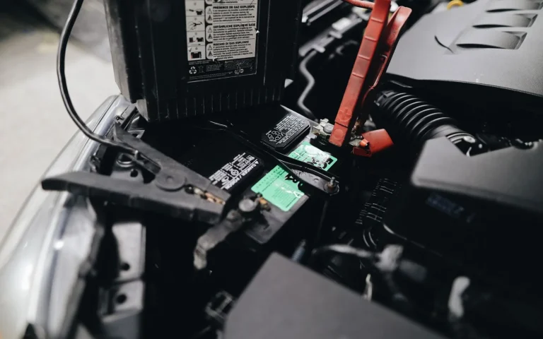 Robot mower docked on its charging base in shade with battery indicator visible