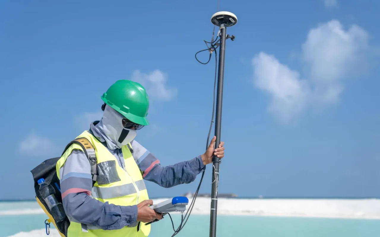 RTK GPS reference antenna mounted on a pole above a robot mower on an open lawn
