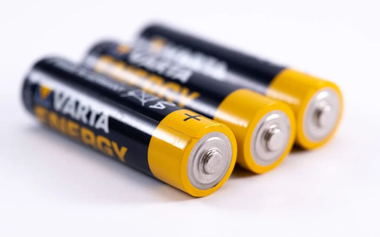 Hands connecting a lithium battery pack inside a robot lawn mower on grass