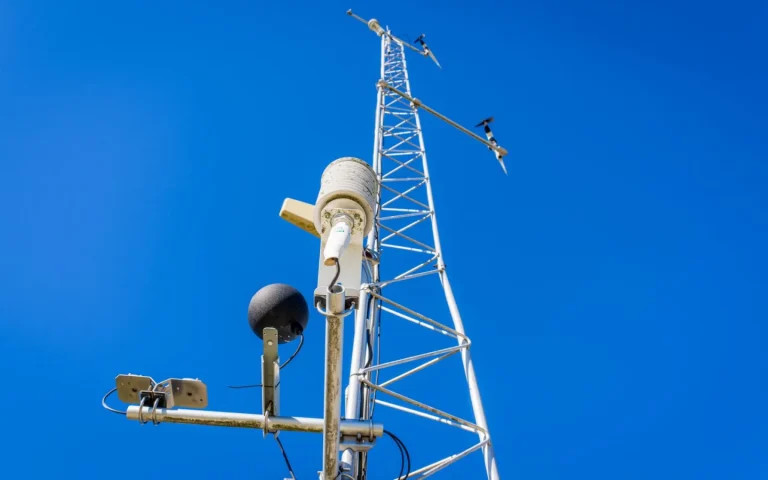 RTK reference antenna mounted high on a pole with open sky above a lawn