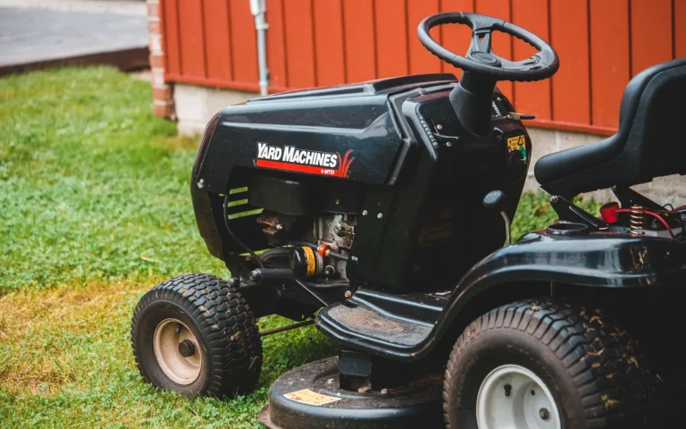 Person flipping over a robot lawn mower on the grass to inspect the underside for noise