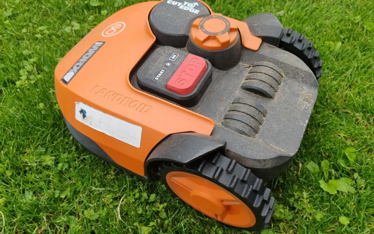 Close-up of the underside of a robot lawn mower showing sensors and cutting blade