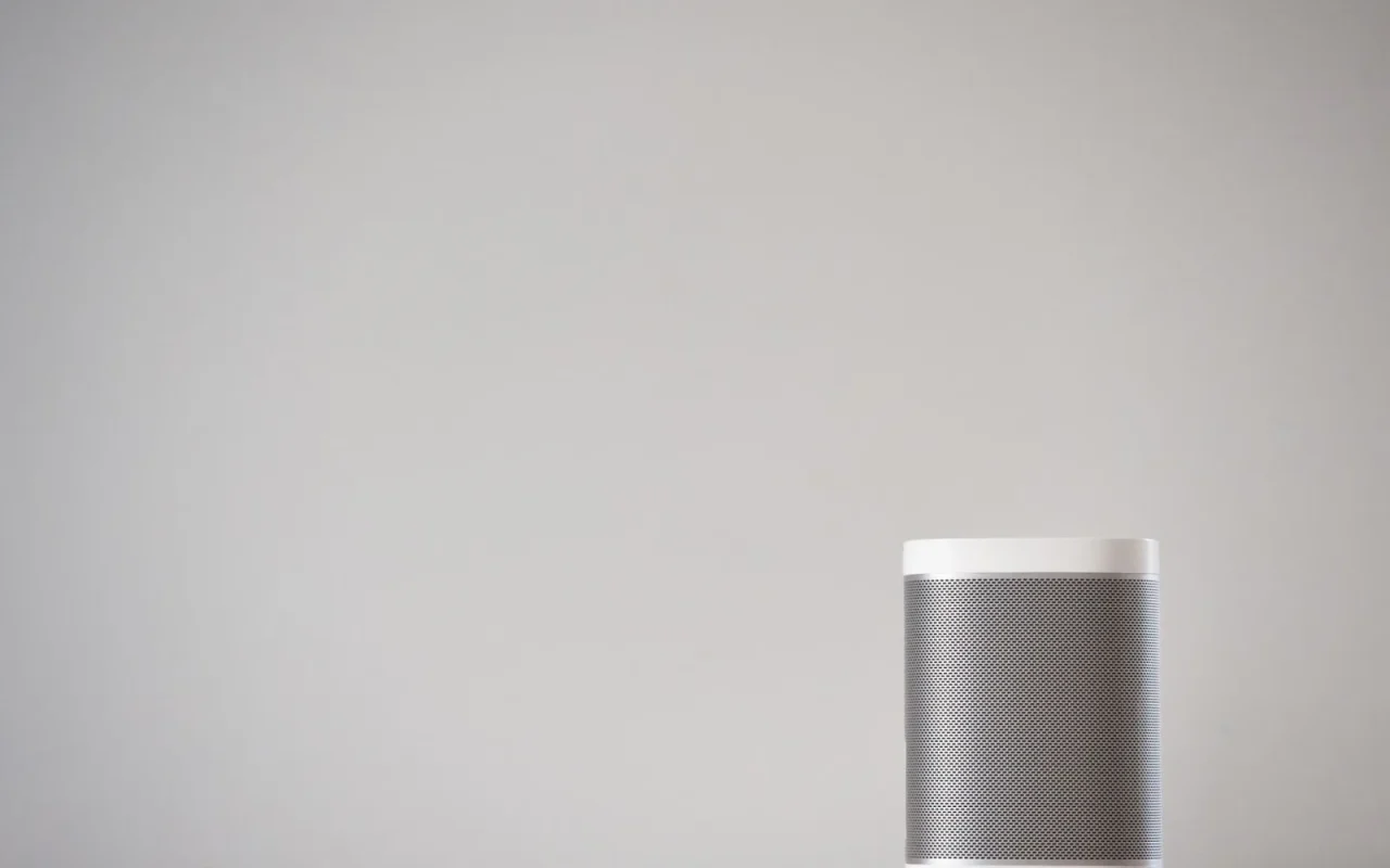 Smart speaker on a shelf near a window with a robot mower visible outside