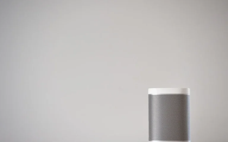 Smart speaker on a shelf near a window with a robot mower visible outside