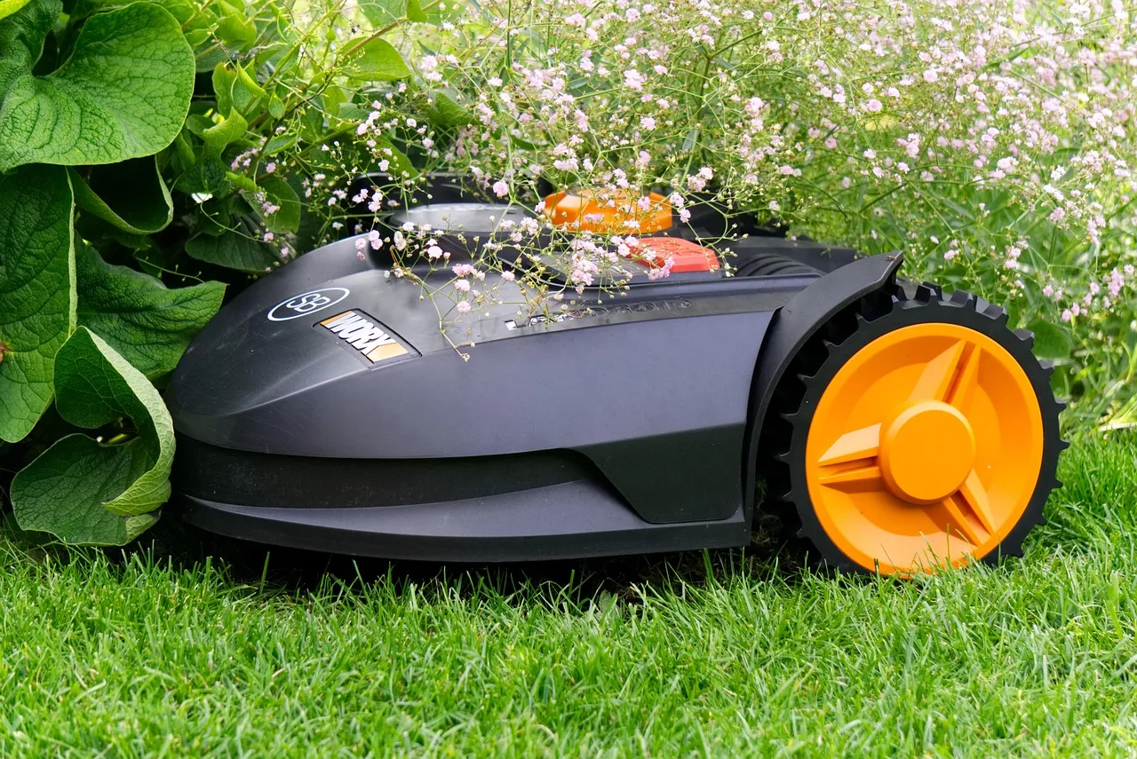Robot mower parked on an open front lawn under a clear sky