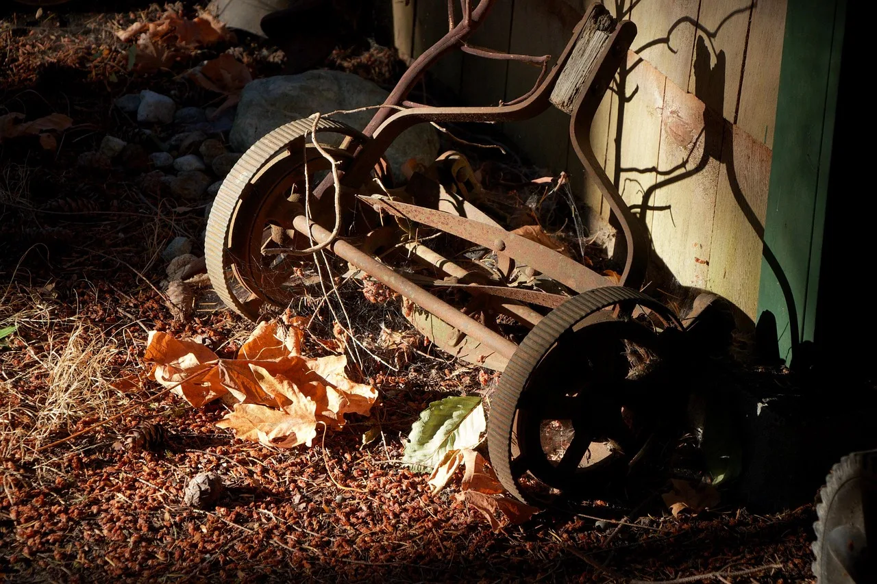 Person scraping grass clippings from the underside of a robot mower before storage