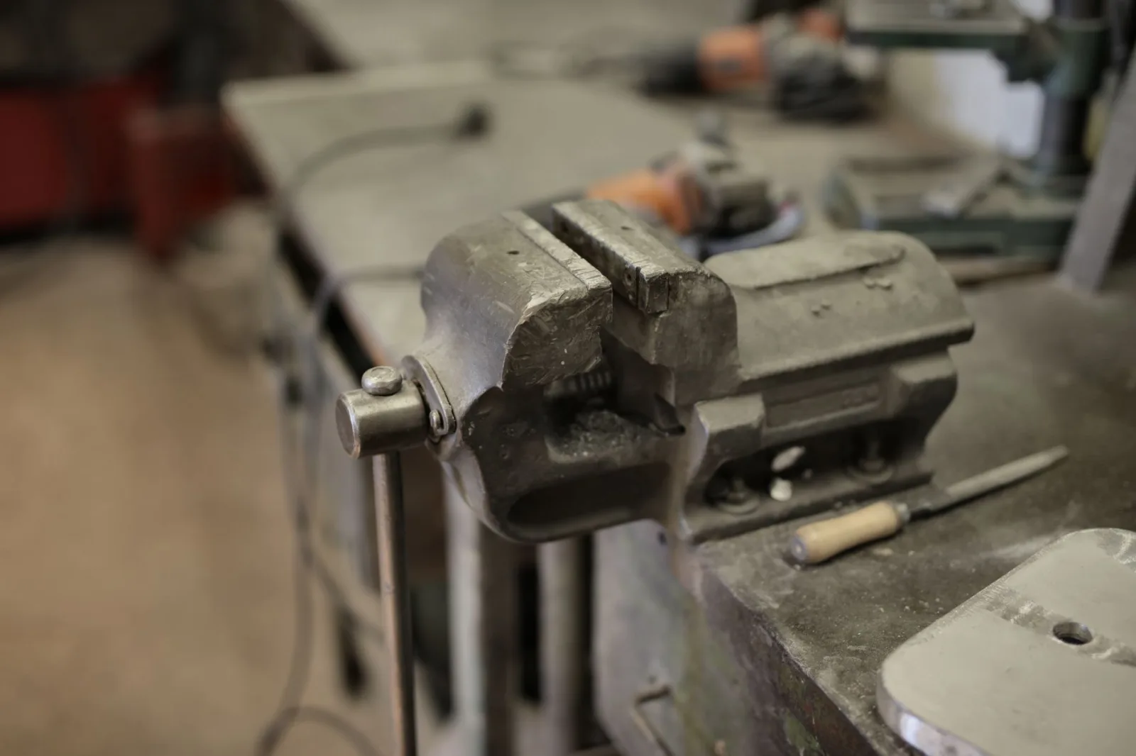 Robot mower on a bench beside a screwdriver, brush, and fresh blades during annual service