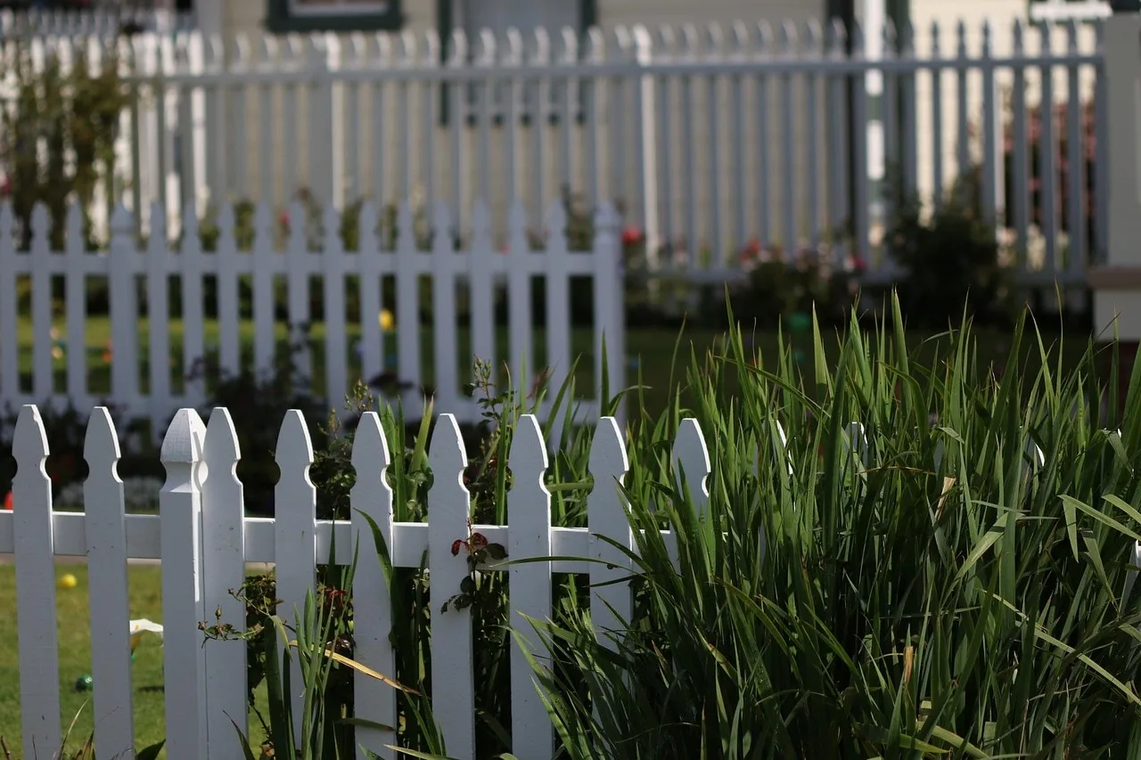 Robot mower docked in a private backyard screened from the street by a fence