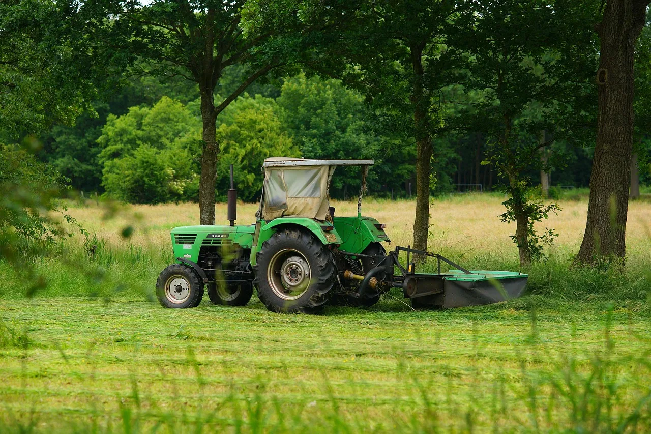 Gloved hand removing a twig jammed against a robot mower blade disc