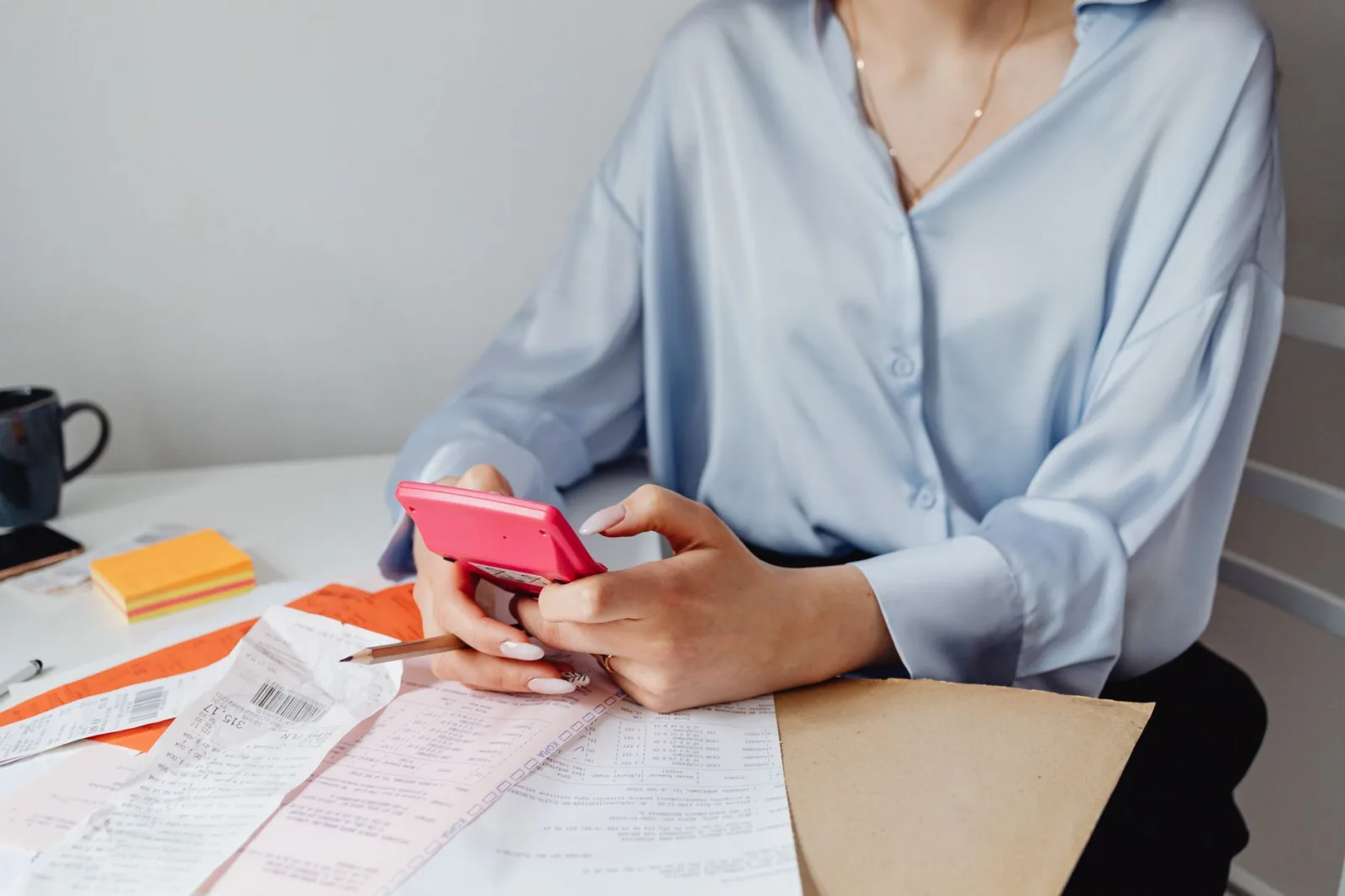 Homeowner using a calculator and phone to compare robot mower payment plans at a desk