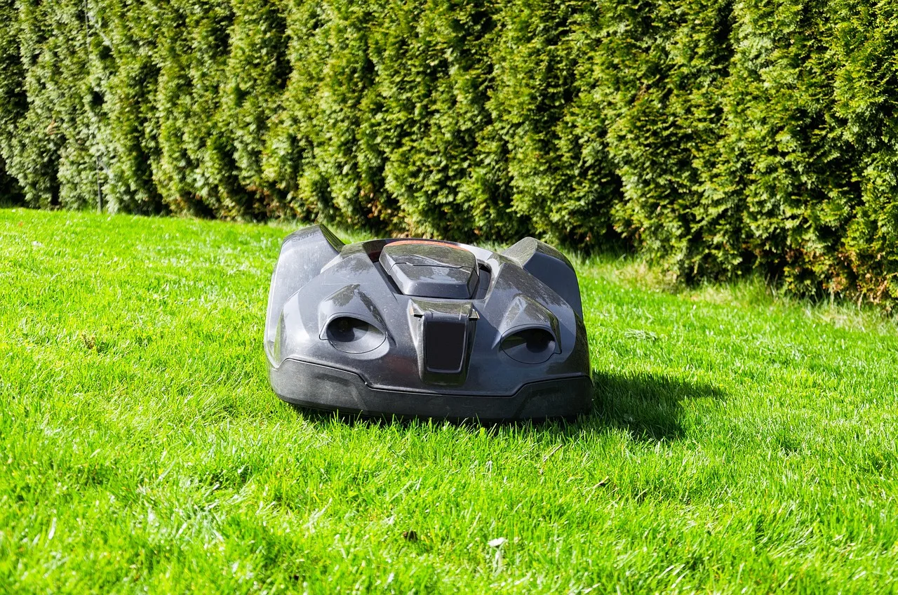 Robot mower docked on its charging base at the edge of a lawn