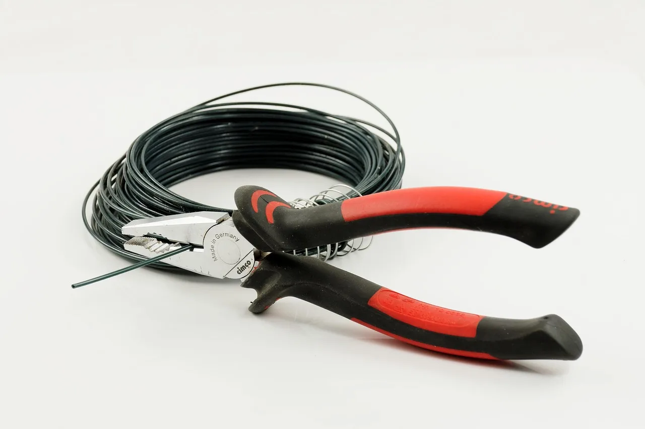 Wire cutters and pliers resting on lawn beside boundary wire and pegs