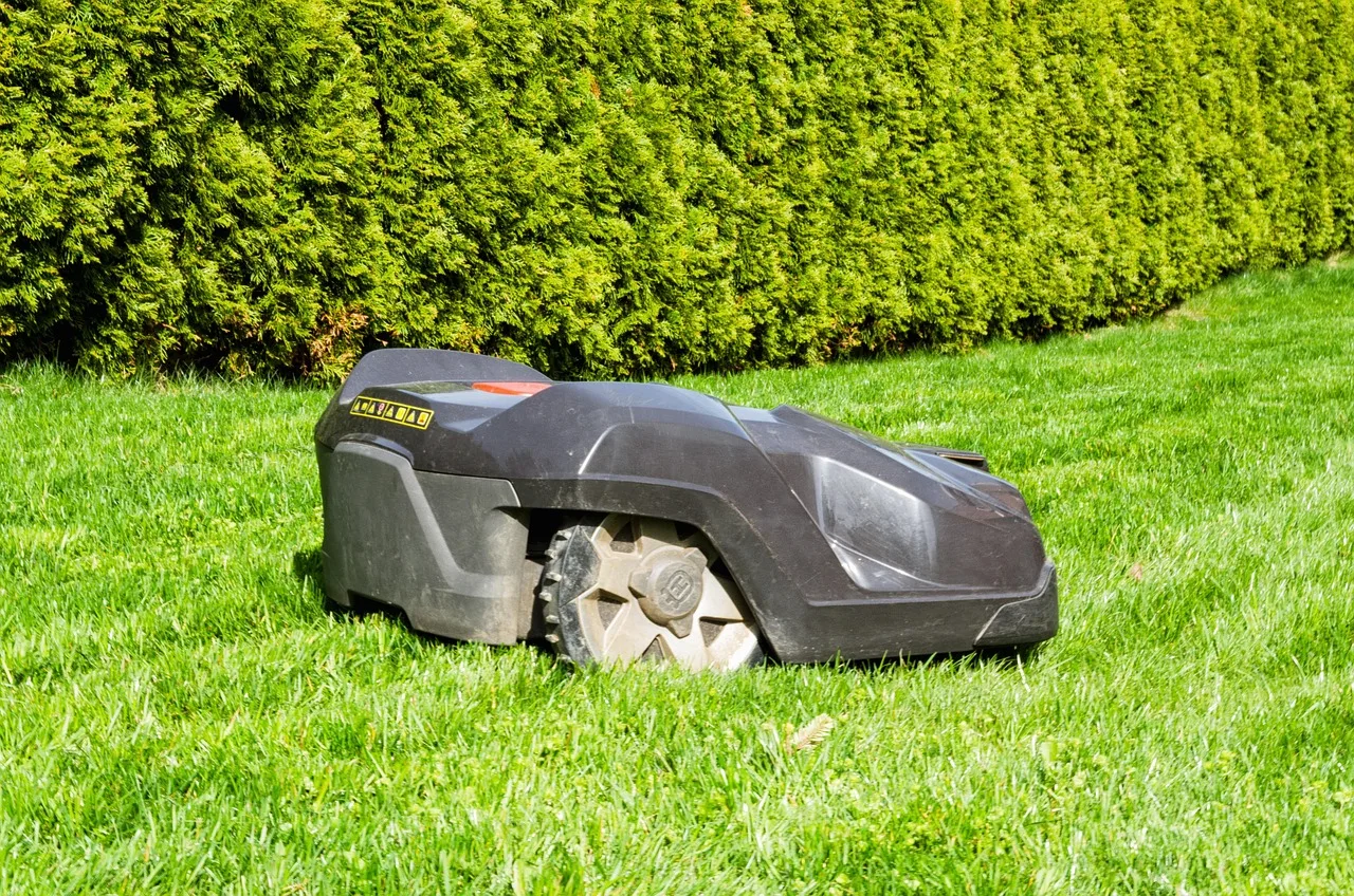 Close-up of a robot mower drive wheel with grass and mud packed in the tread
