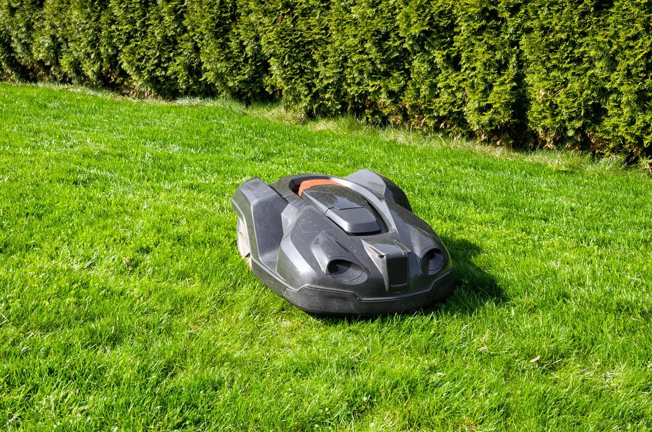 Robot mower crossing a uniformly cut green lawn without visible stripes