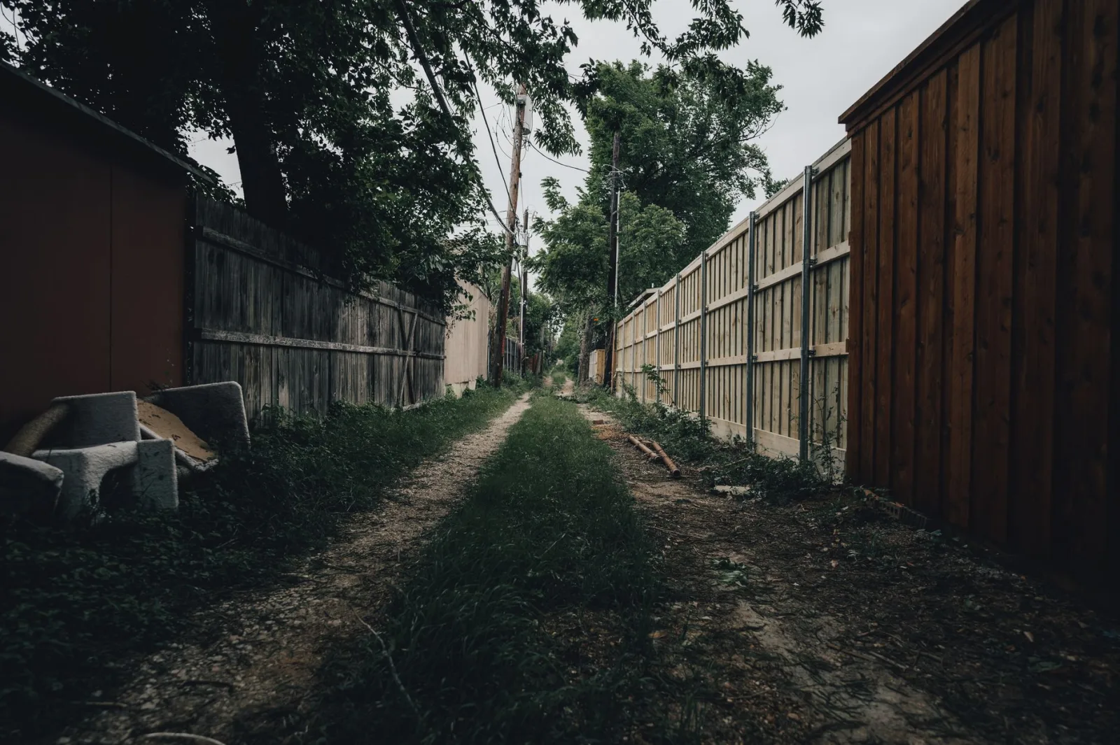 Narrow strip of lawn between a fence and wall forming a tight mower passage