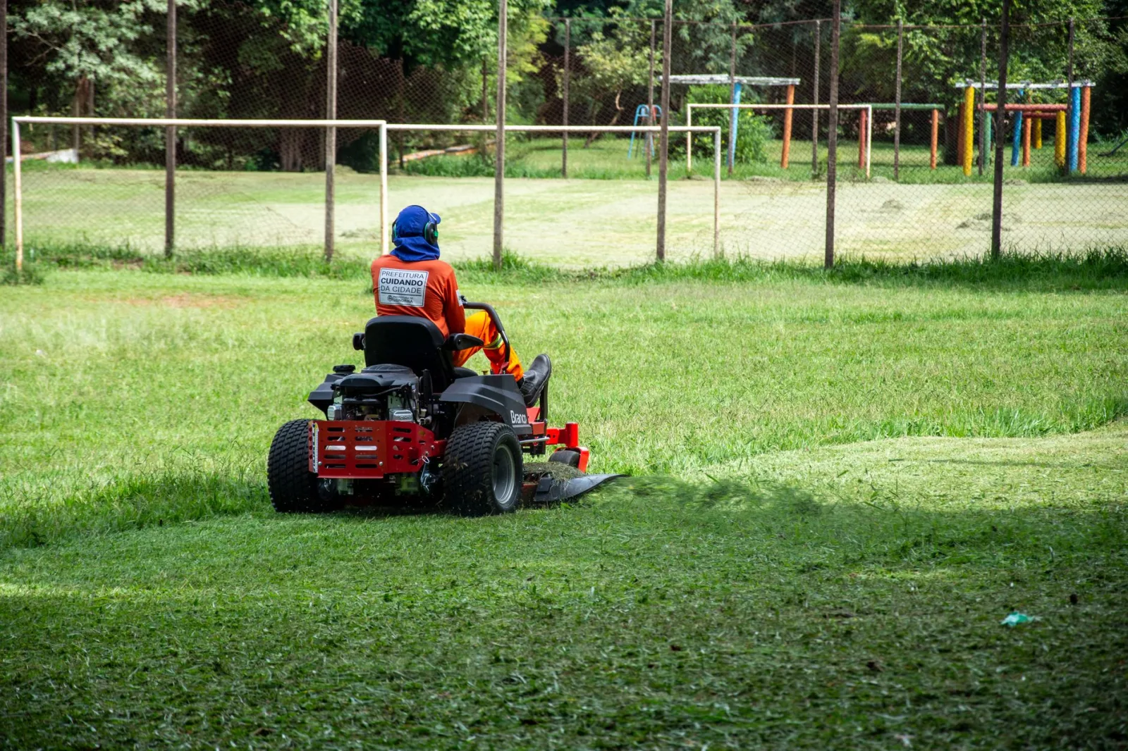 Owner lifting a robot mower by its handle to move it between lawns