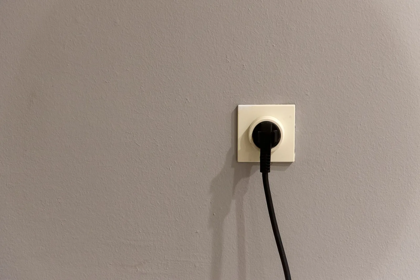 Weatherproof cover over an outdoor electrical outlet beside a garden wall