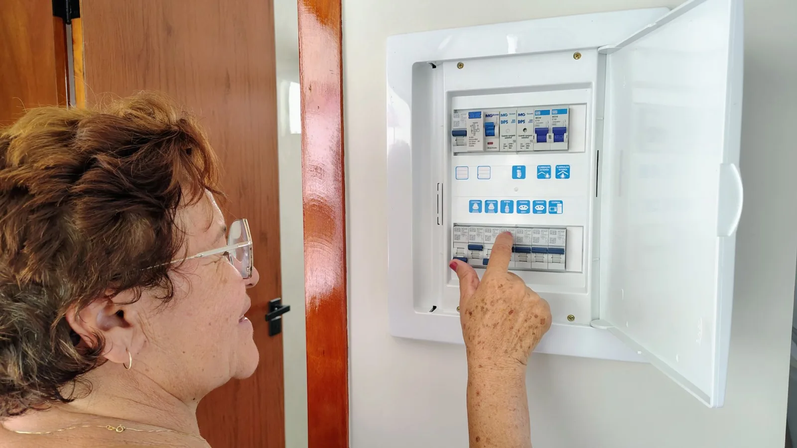 Home electrical breaker panel with a hand resetting a tripped switch