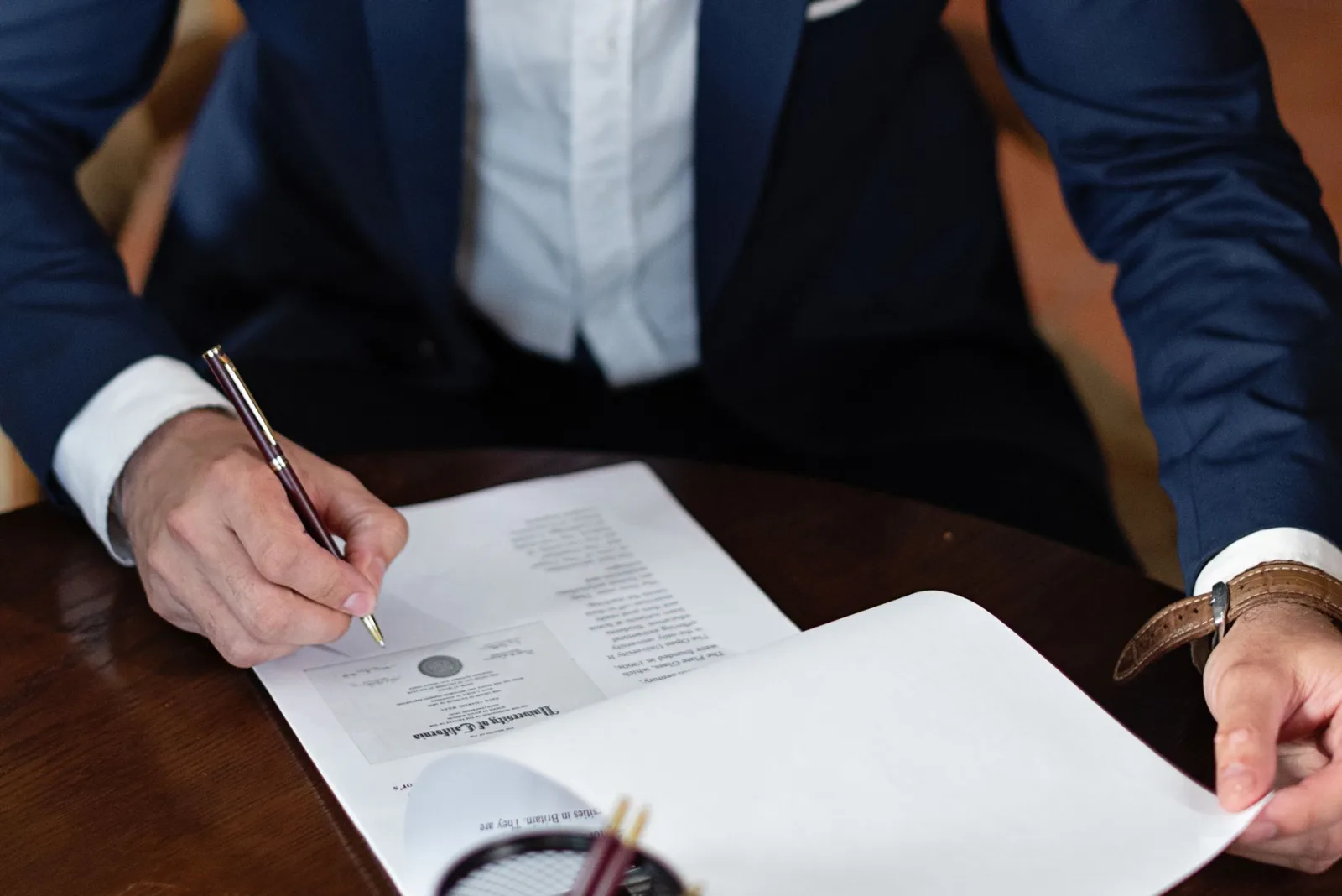 Person reading a printed warranty document at a kitchen table before registering a purchase