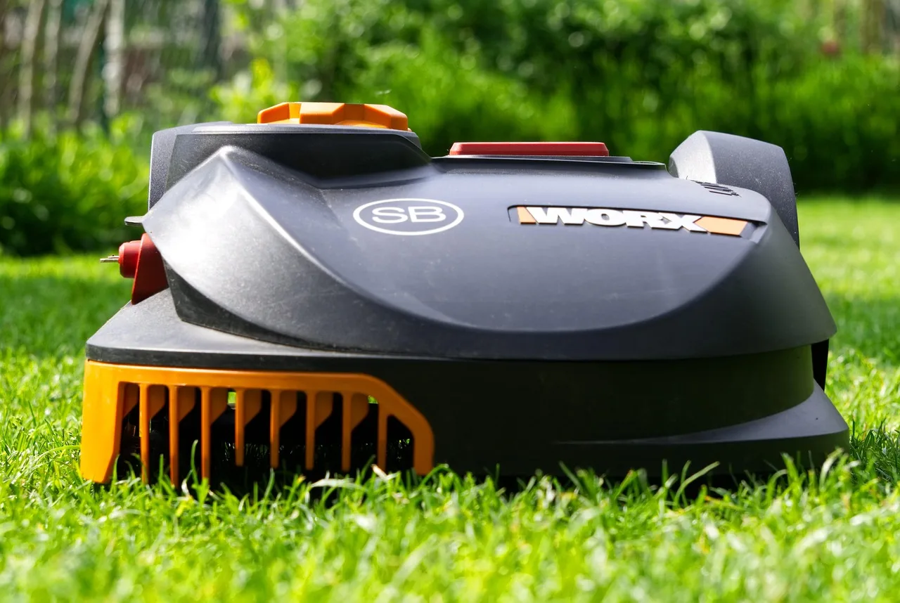 Robot mower passing through a narrow grass passage between two garden areas