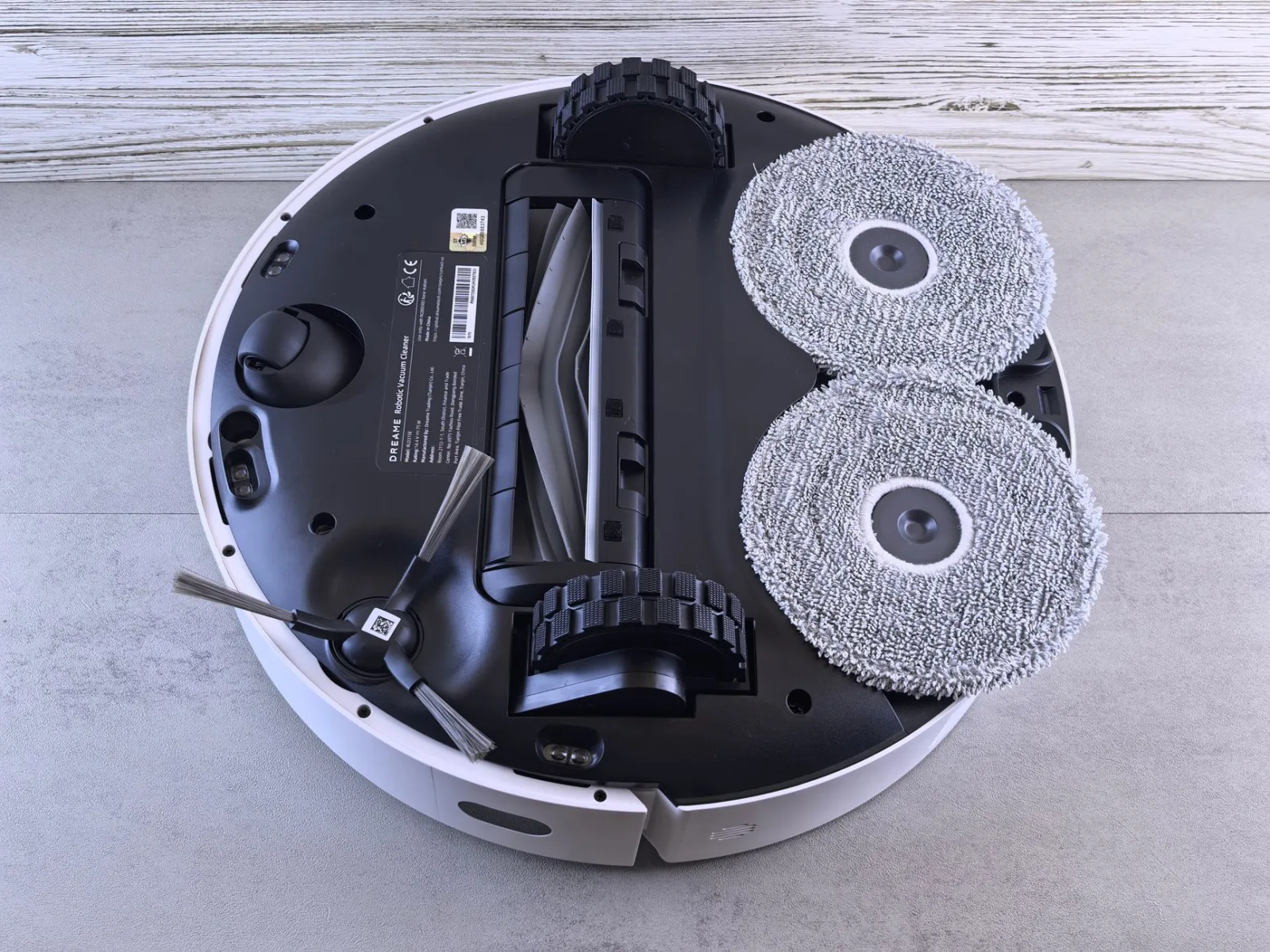 Hands turning a robot mower over to inspect the blade disc and wheels underneath