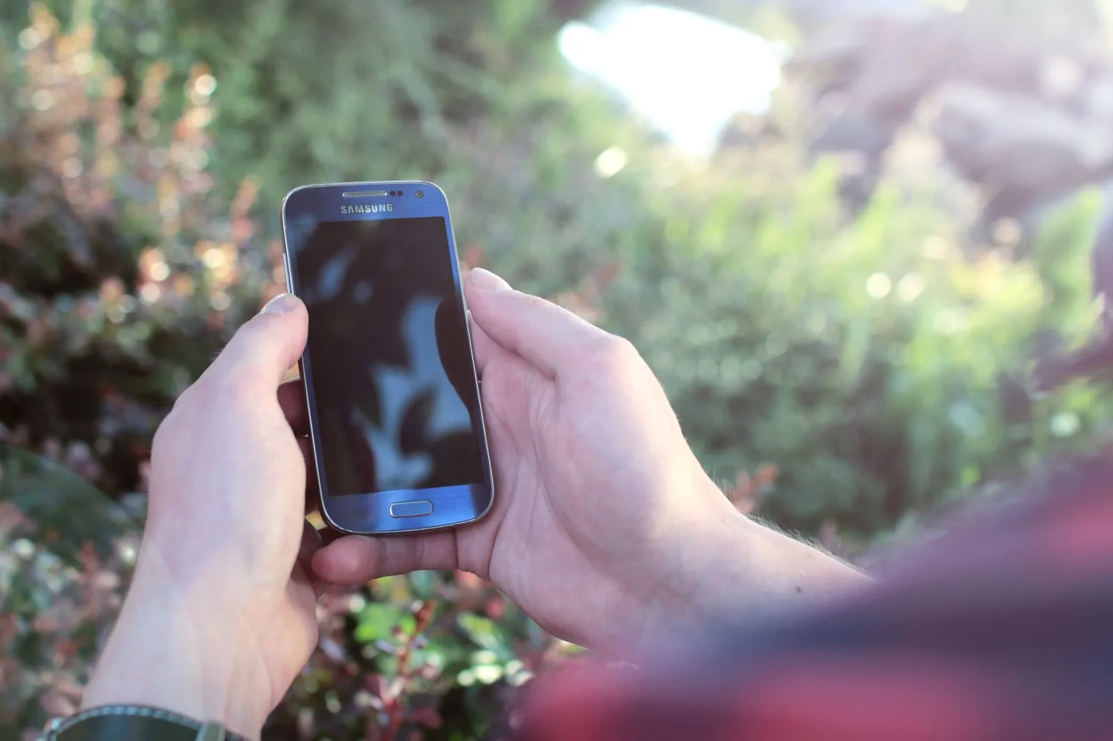 Buyer checking a robot mower app on a phone to confirm account release outdoors